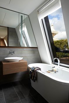 a bathroom with a bathtub, sink and large window looking out onto the outdoors