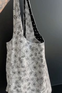 a black and white bag with spider webs on the front is hanging from a hook