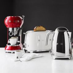 two toasters and a coffee maker on a white counter with black backround