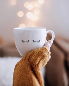 a person holding a coffee cup with eyelashes on it