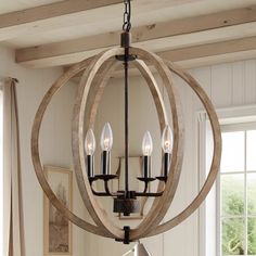 a wooden chandelier hanging from the ceiling in a room with white walls and windows