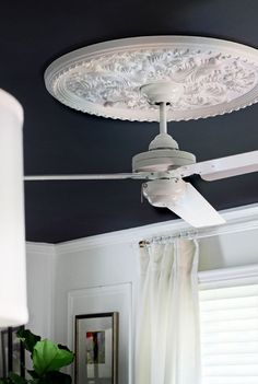 a white ceiling fan mounted to the side of a wall in a room with blue walls