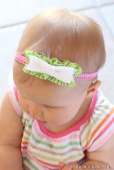 a baby girl wearing a green and white headband with a bow on it's side