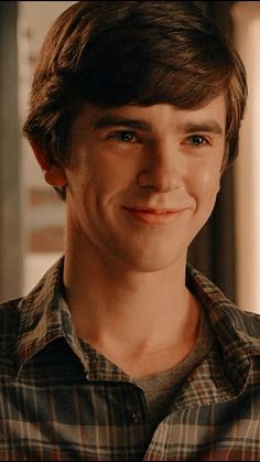 a smiling young man wearing a plaid shirt