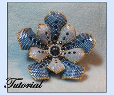 a blue and white flower brooch sitting on top of a gray table next to a light blue background