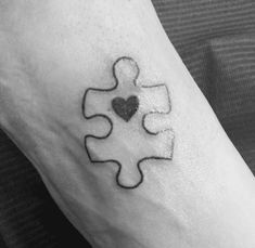 a black and white photo of a person's foot with a puzzle piece tattoo on it