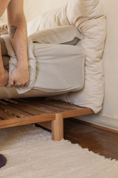 a man standing on top of a bed with his foot propped up against the pillow