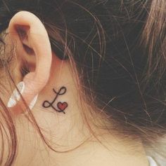 a woman with a tattoo on her left ear and behind the ear is a pair of scissors