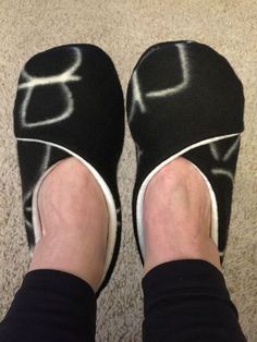 someone wearing black slippers with white writing on them