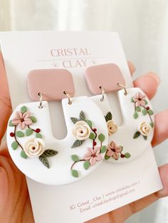 a pair of white and pink flower earrings on top of a piece of paper that says crystal clay