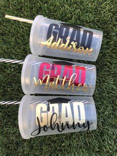 three personalized water bottles with straws in them sitting on the grass next to each other