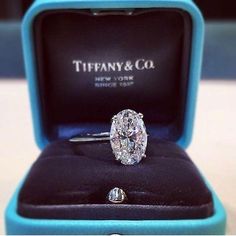 an oval cut diamond ring in a blue box with the logo tiffany & co on it