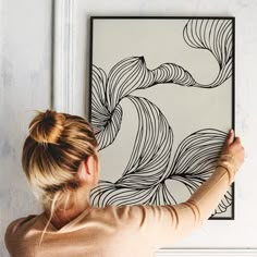 a woman is holding up a black and white painting