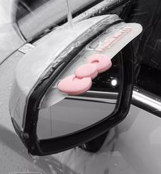 a pair of pink doughnuts are on the side mirror of a silver car