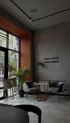 a room with chairs, tables and a sign on the wall that says work hard chill smart