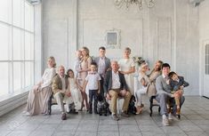 a group of people posing for a photo in a room with large windows and a chandelier