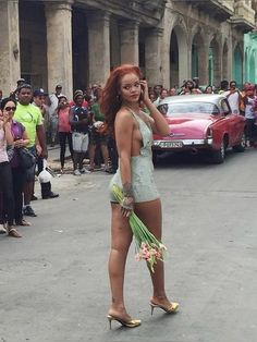 a woman is walking down the street talking on her cell phone and holding flowers in her hand