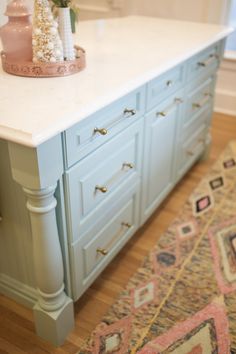 a white counter top sitting on top of a wooden floor next to a pink vase