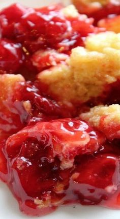 a white plate topped with strawberry shortcakes covered in jelly sauce and crumbs