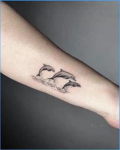 two dolphins jumping out of the water tattoo on the left forearm and right hand arm