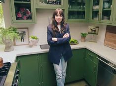 a woman standing in a kitchen with green cabinets