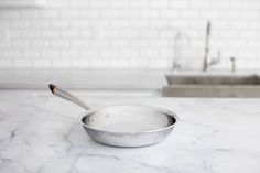 a silver pan sitting on top of a white counter next to a kitchen faucet