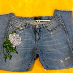 a pair of jeans with flowers painted on the front and back, sitting against a yellow background