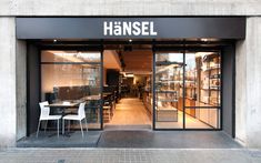 a store front with tables and chairs in the doorway, next to an empty sidewalk