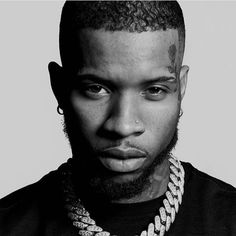 a black and white photo of a man with a beard wearing a chain around his neck