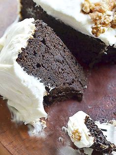 a piece of chocolate cake with white frosting and walnuts on the top slice