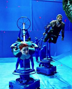 two people in scuba gear standing next to each other on top of blue platforms with one man diving