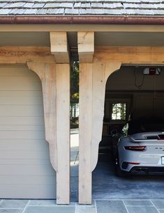 a car parked in front of a garage with two wooden pillars on the side of it