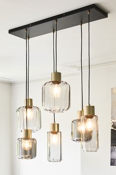 four clear glass pendant lights hanging from the ceiling in a living room with white walls