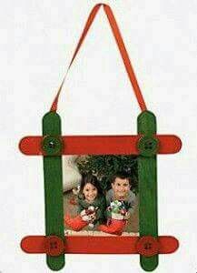 an ornament hanging from a red and green frame with two children on it