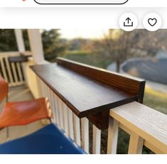 a close up of a wooden rail on a porch next to a chair and tree