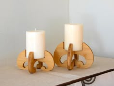 two candles are sitting on a table next to each other, one is made out of wood