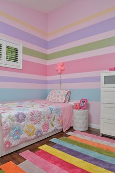 a child's bedroom decorated in pastel colors with striped walls and rugs