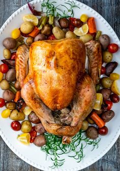 a roasted turkey on a platter with potatoes, carrots, and other vegetables