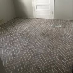 an empty room with a door and brick flooring on the ground in front of it