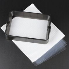 three pieces of white paper are stacked on top of each other, with a black tray in the middle