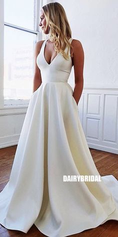 a woman standing in front of a window wearing a white wedding dress with deep v - neck