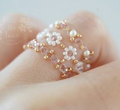 a close up of a person's hand holding a ring with pearls on it