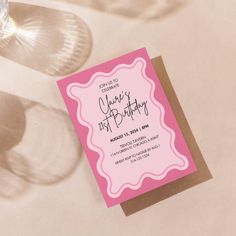 a pink and brown birthday card sitting on top of a table next to wine glasses