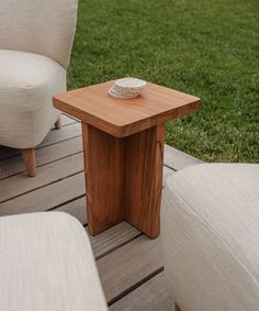 a wooden table sitting on top of a wooden floor next to two white couches