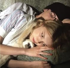 a woman laying on top of a couch next to a man holding a small dog