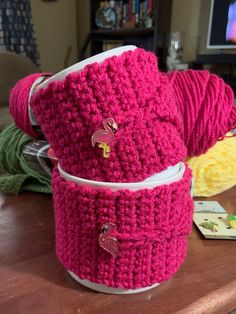 two crocheted cups sitting on top of a wooden table