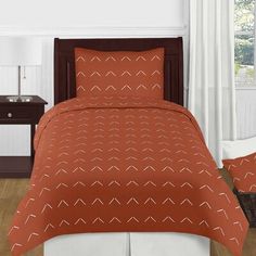 a bed with an orange comforter and two pillows