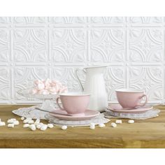 two pink cups and saucers with marshmallows on the table next to them