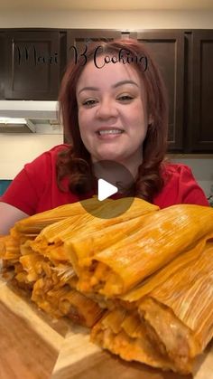 a woman sitting in front of a wooden cutting board with some food on top of it