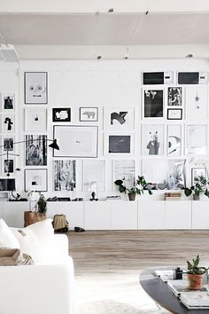 a living room filled with furniture and lots of pictures on the wall above it's coffee table